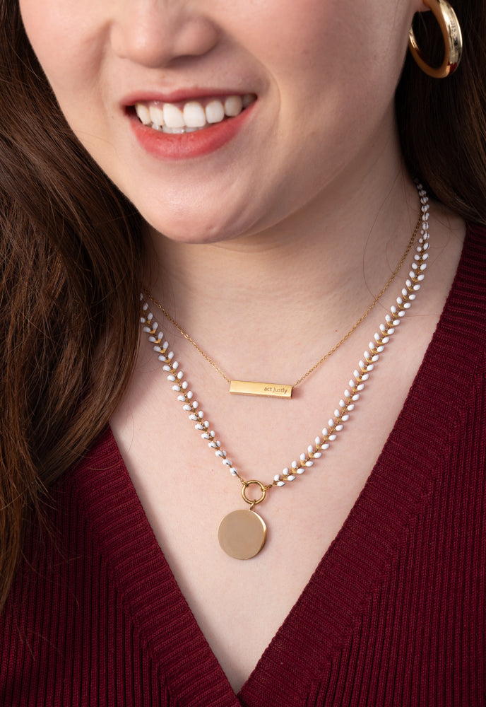 Model wearing ivory Seeds of Hope chain layered with a gold engravable bar necklace
