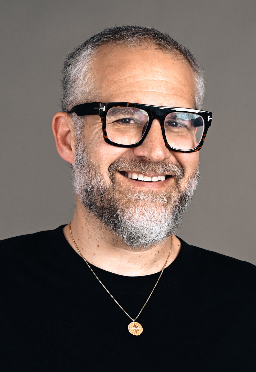 Smiling man with gray beard and glasses in a black t-shirt