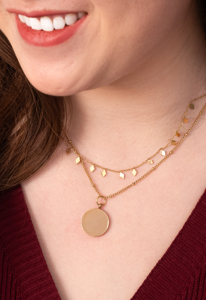 Close-up of model wearing Engravable gold disc necklace layered with a charm chain