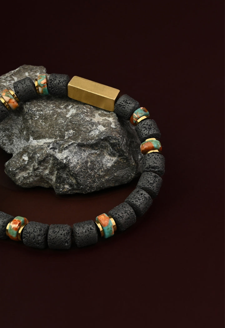 Legacy bracelet black lava beads, emperor stone accents and gold bar on dark stone