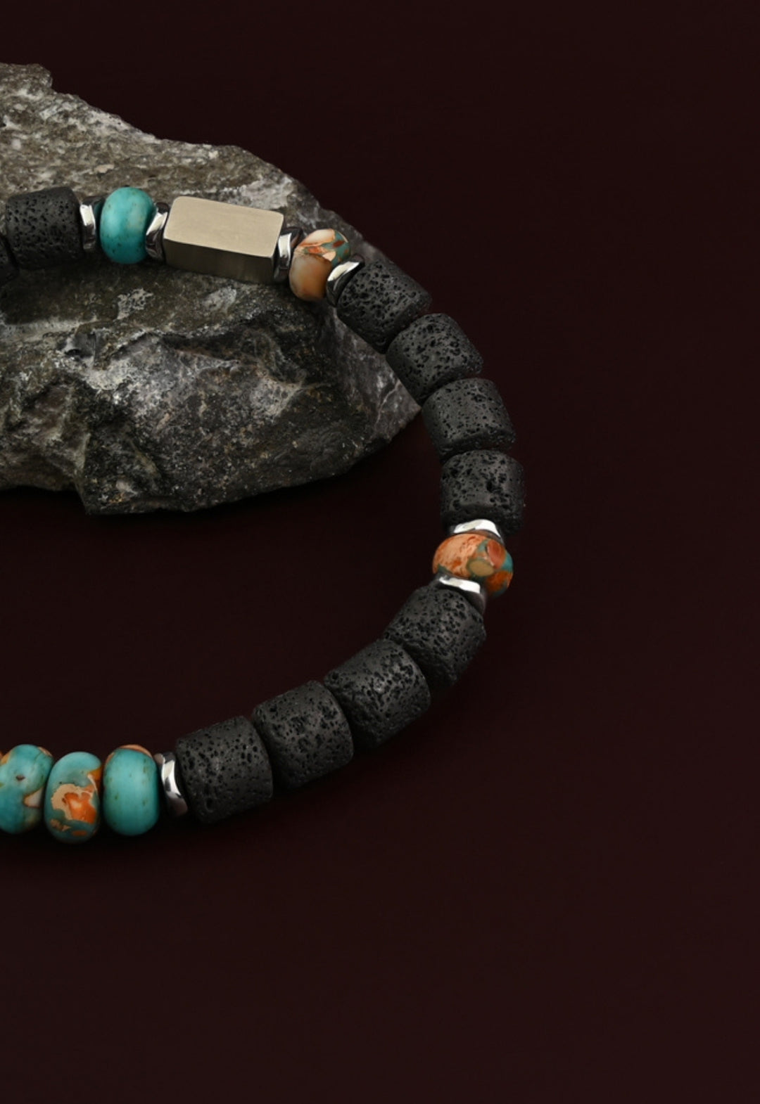 Strength lava bead and turquoise emperor stone bracelet on a gray rock