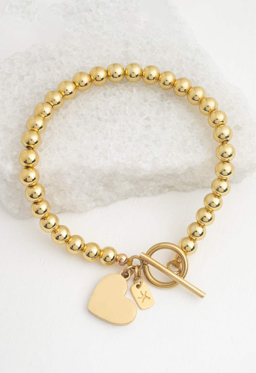 Hand-beaded gold bracelet with toggle clasp on white stone