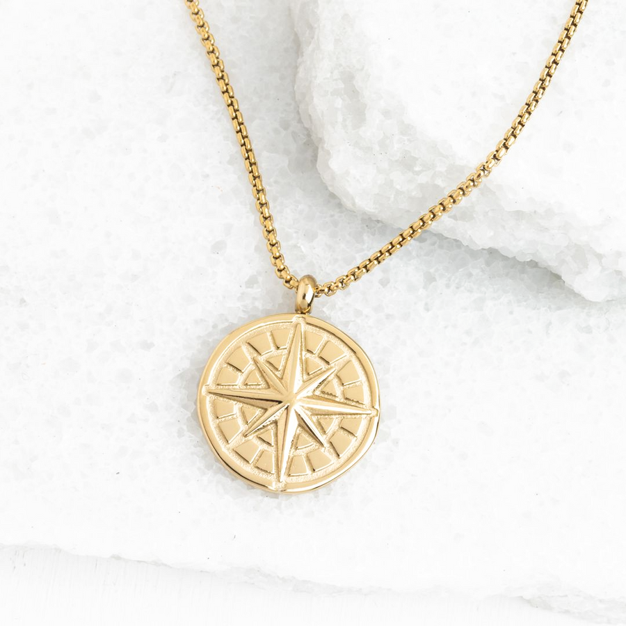 True North gold compass medallion necklace on white stone