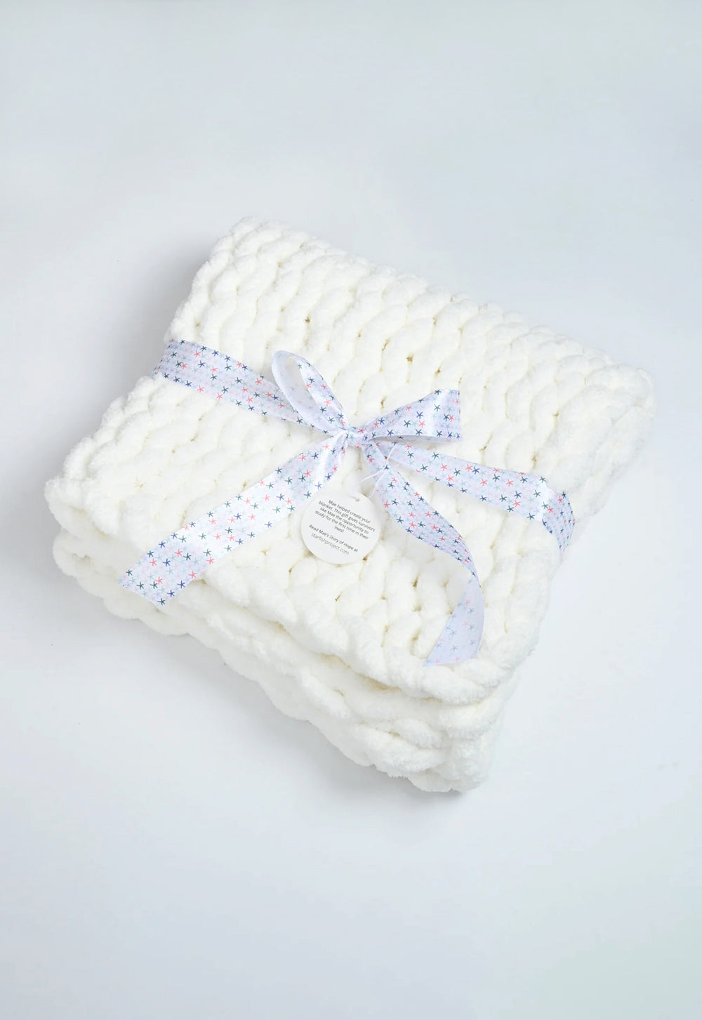 Woven Together white chunky knit baby blanket tied with a ribbon bow