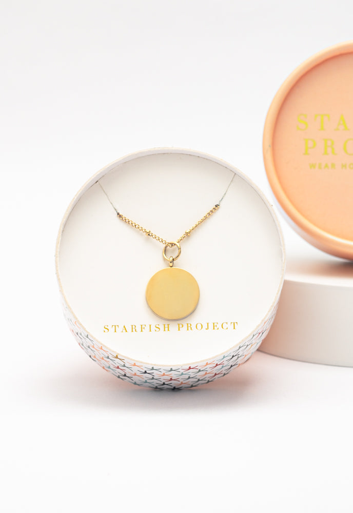 Engravable round gold pendant necklace in a Starfish Project round gift box