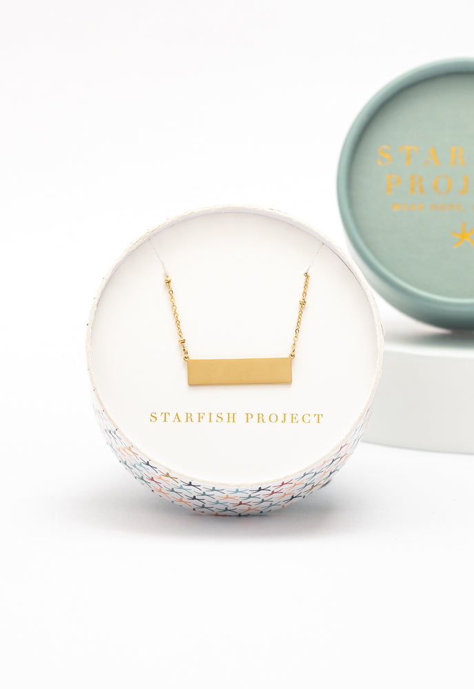Engravable gold bar necklace in a Starfish Project round gift box